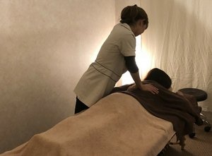 ベッドに横たわるお客様に背中の施術を行うスタッフ
